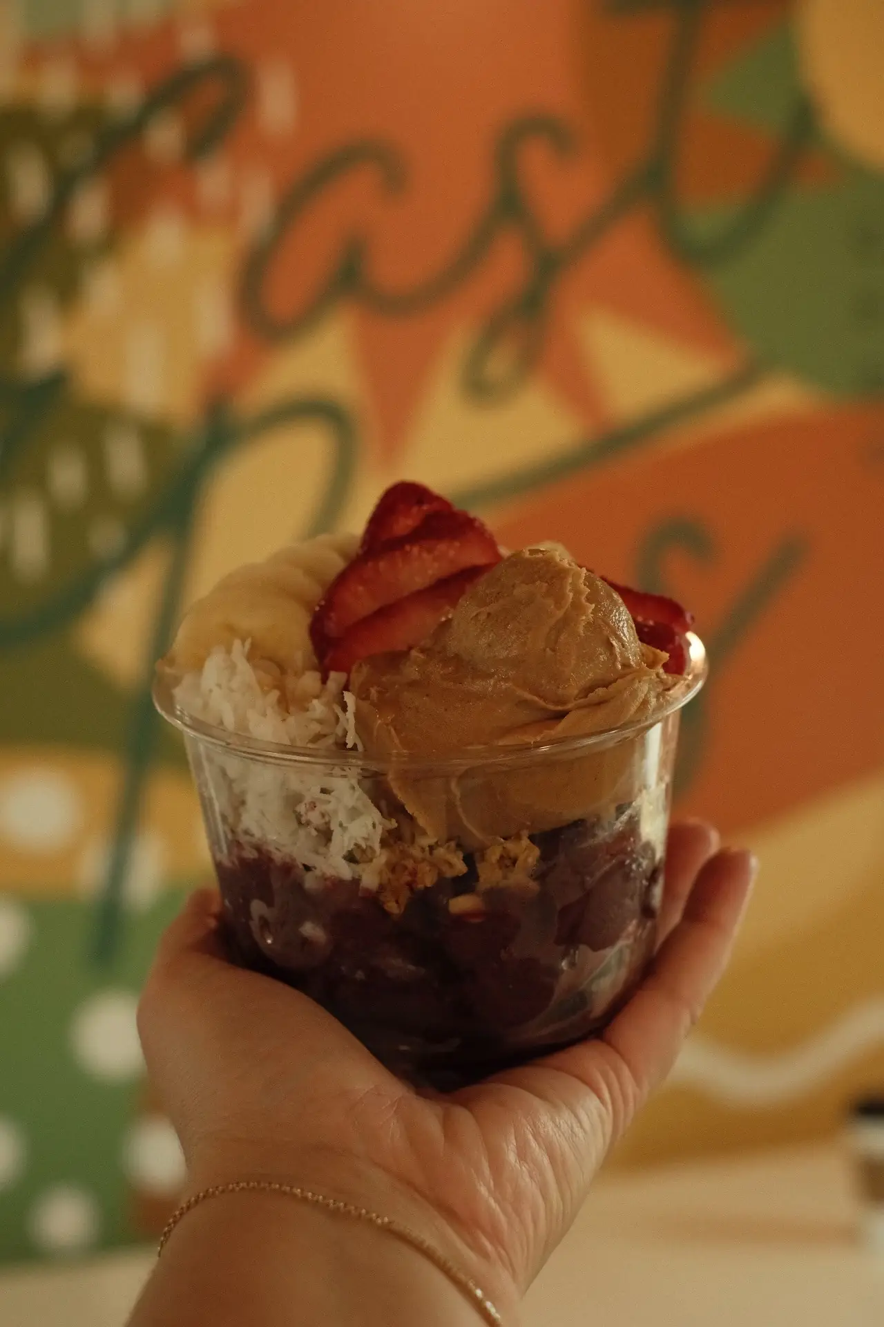 Acai bowl held up in front of the mural