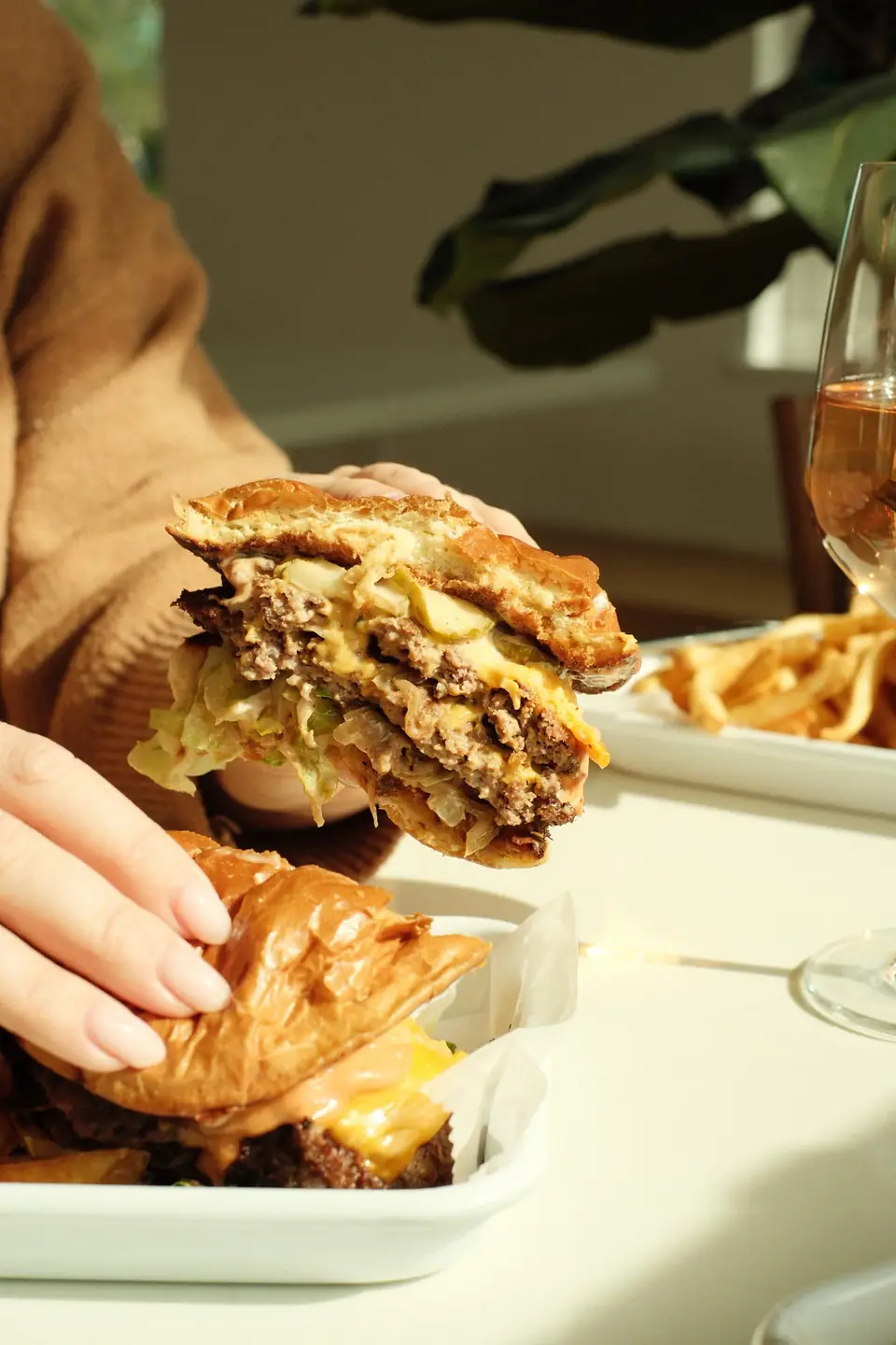 Double smash burger held over a tray of fries